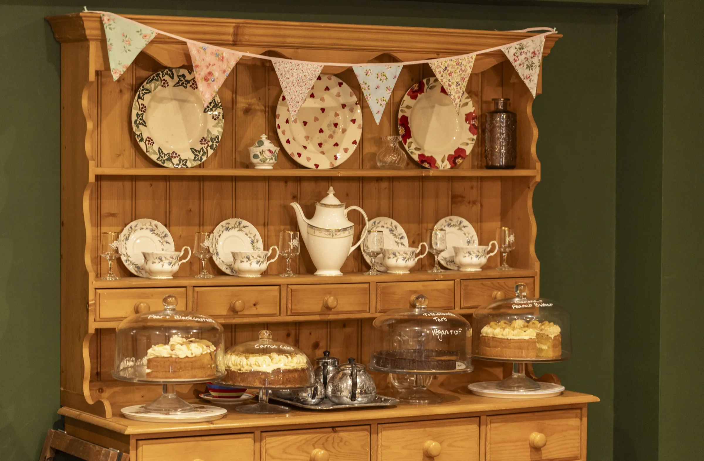 Homemade cakes under glass on the café dresser, with teacups and a teapot