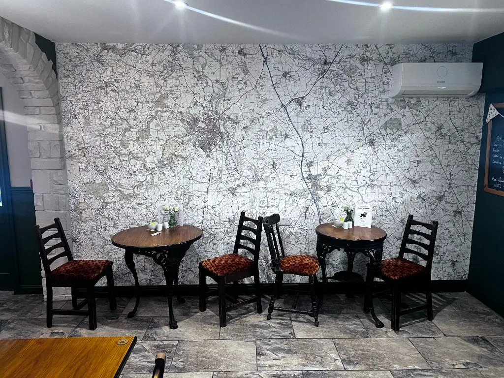 Café seating beside the map wall at The Black Lion, with Skelton-on-Ure marked you are here