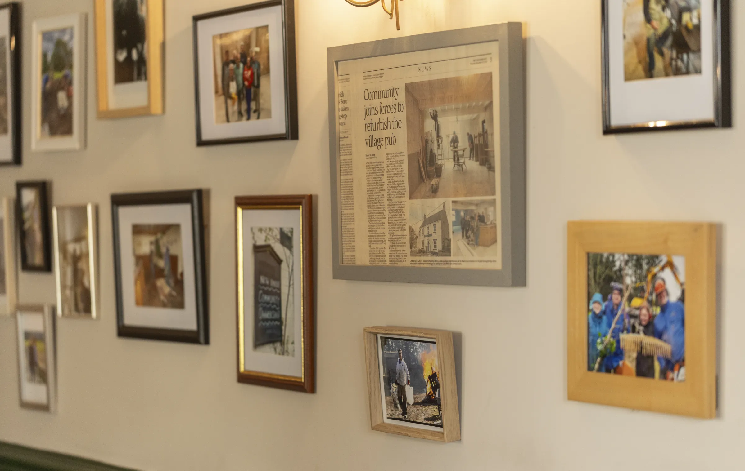 Framed photographs and a newspaper clipping about the village restoring the pub