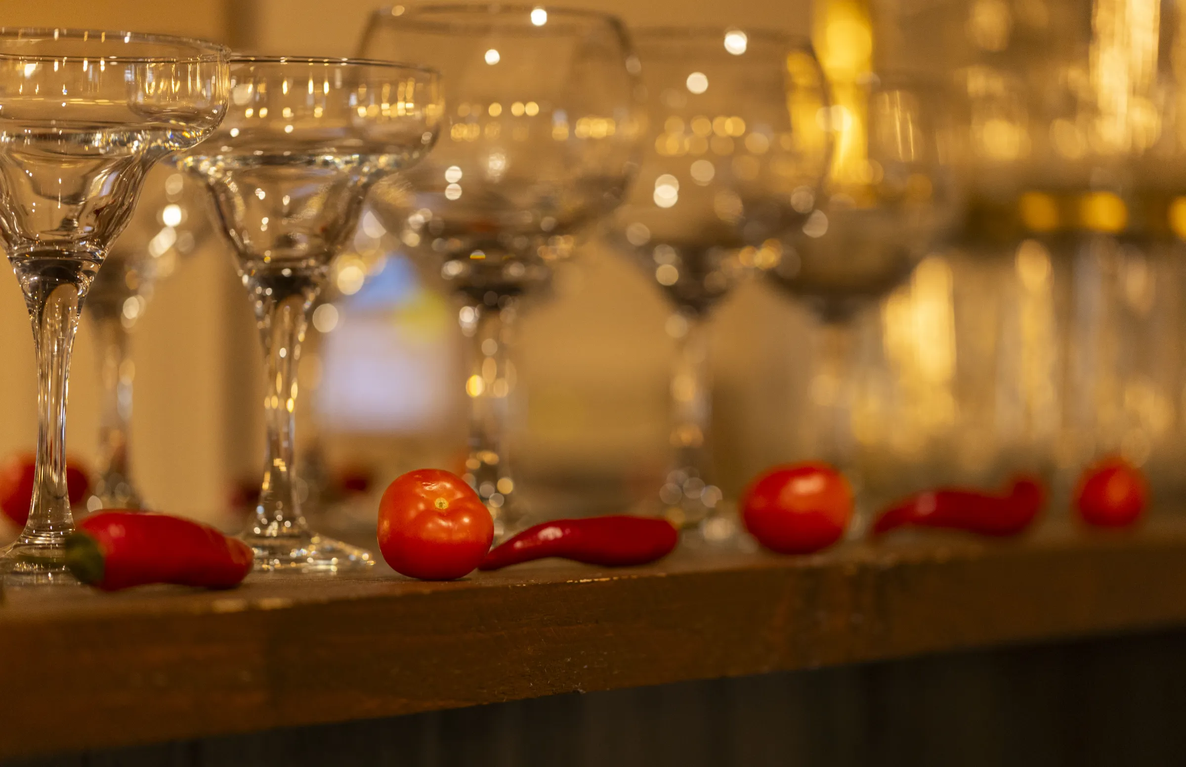 Margarita glasses lined along the bar with chillies and tomatoes