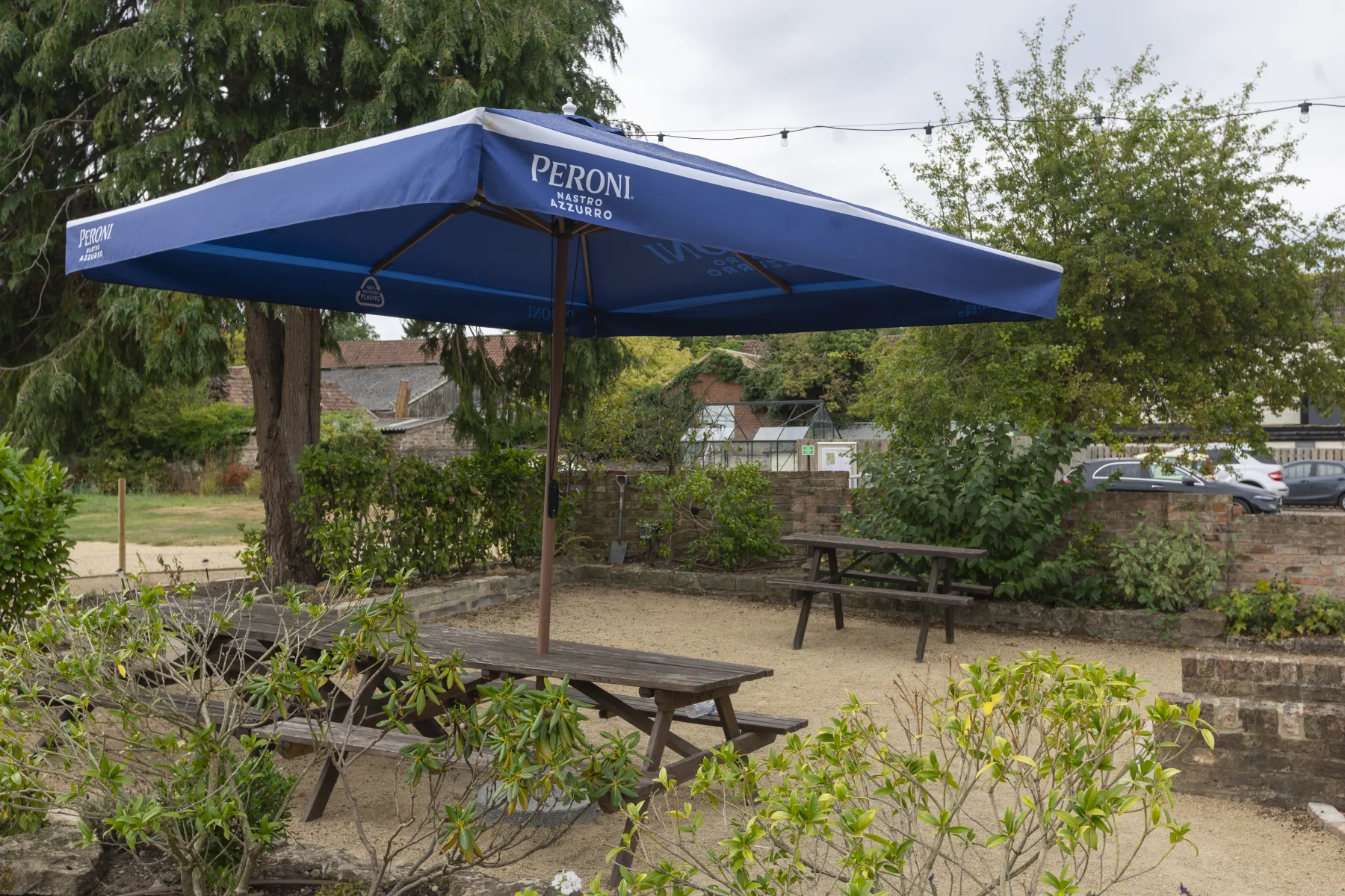 Picnic tables and a Peroni umbrella in the beer garden at The Black Lion