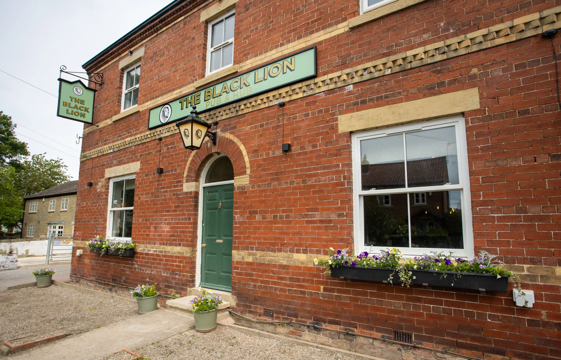 The brick frontage and green entrance of The Black Lion