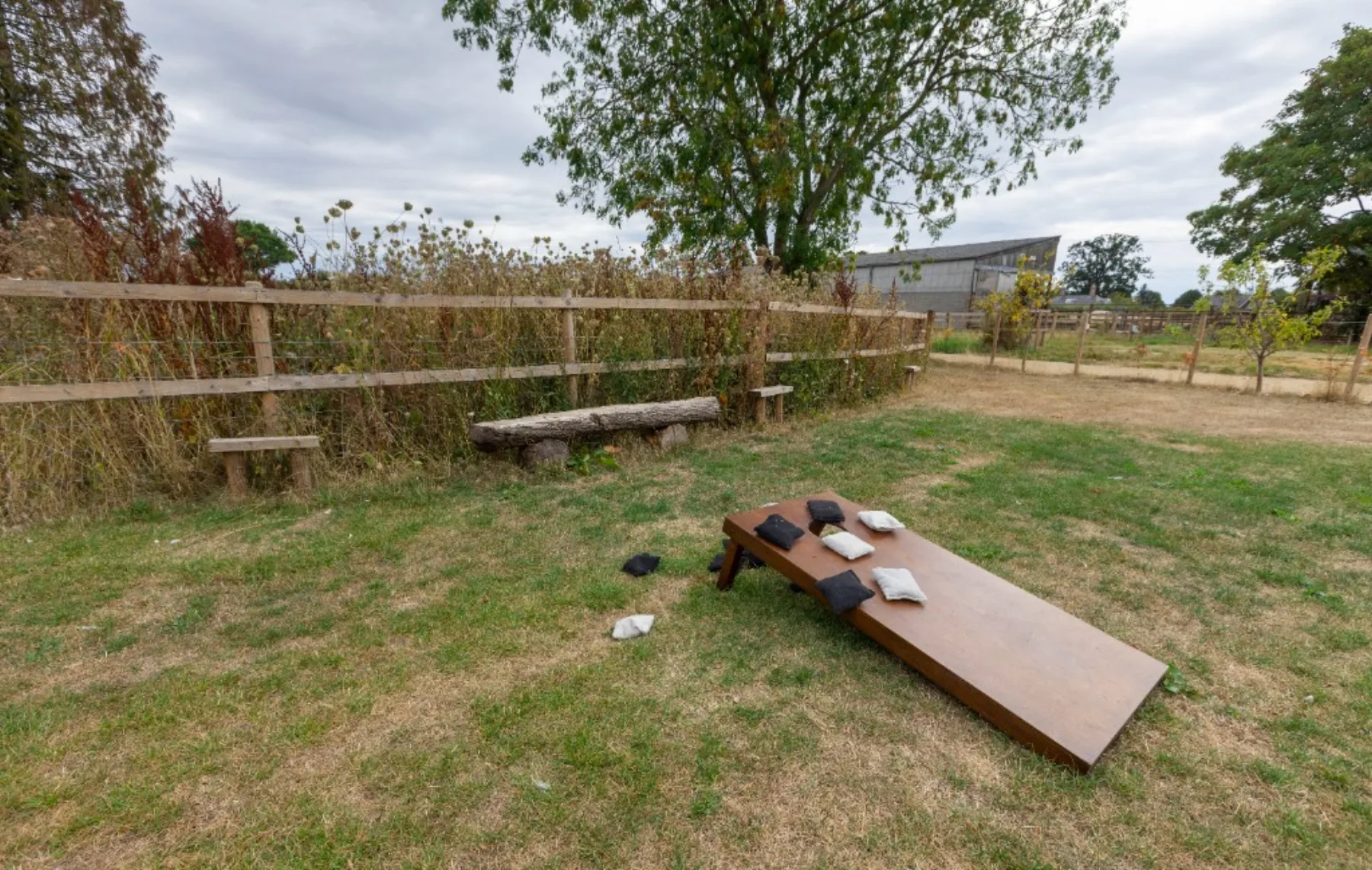 A cornhole board and beanbags on the lawn beside the beer garden