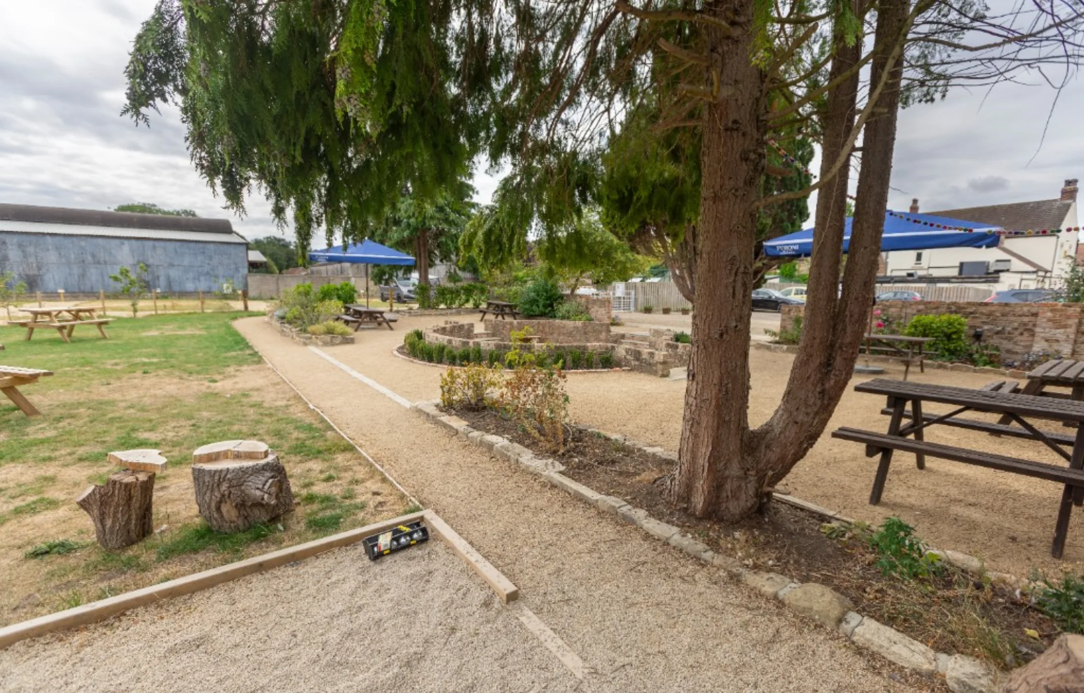 Picnic tables on the lawn, umbrellas and the pétanque pitch at the edge of the garden