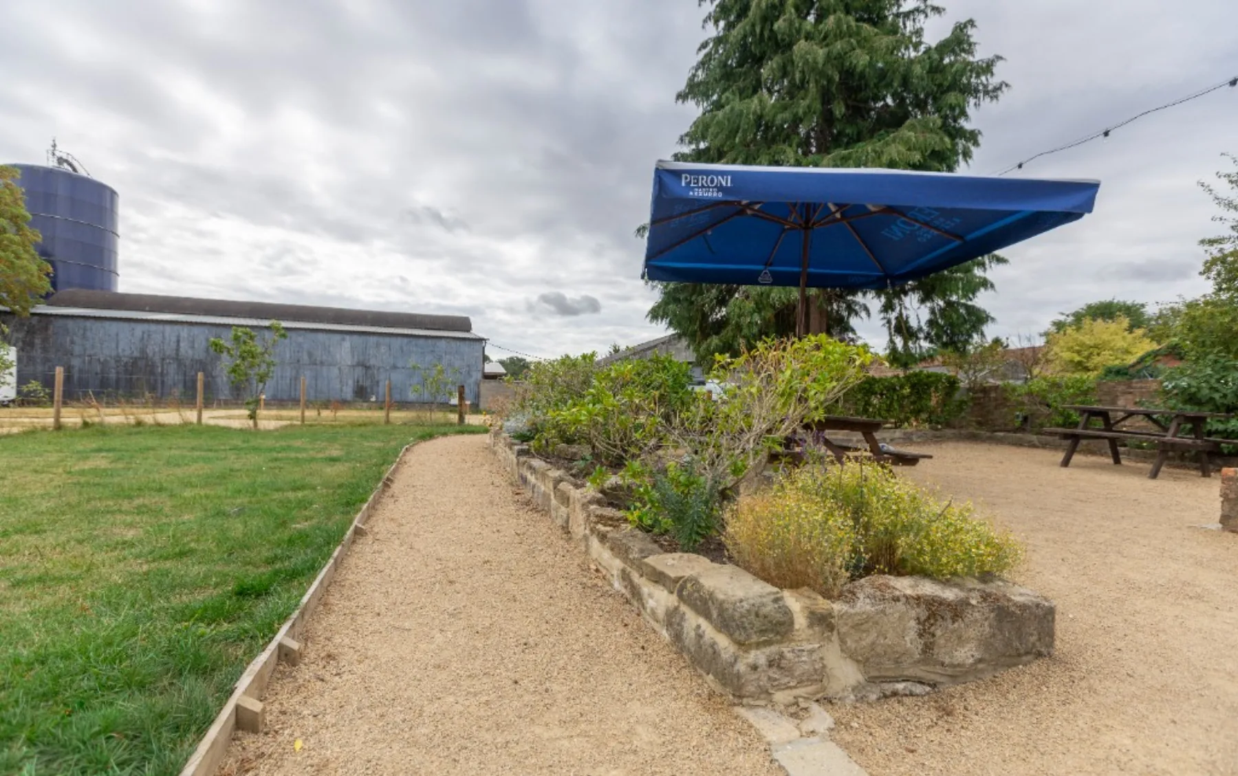 Picnic benches on the gravel terrace beside stone-walled planting
